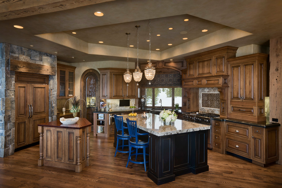 Mountain style kitchen photo in Other with raised-panel cabinets, dark wood cabinets, gray backsplash and paneled appliances