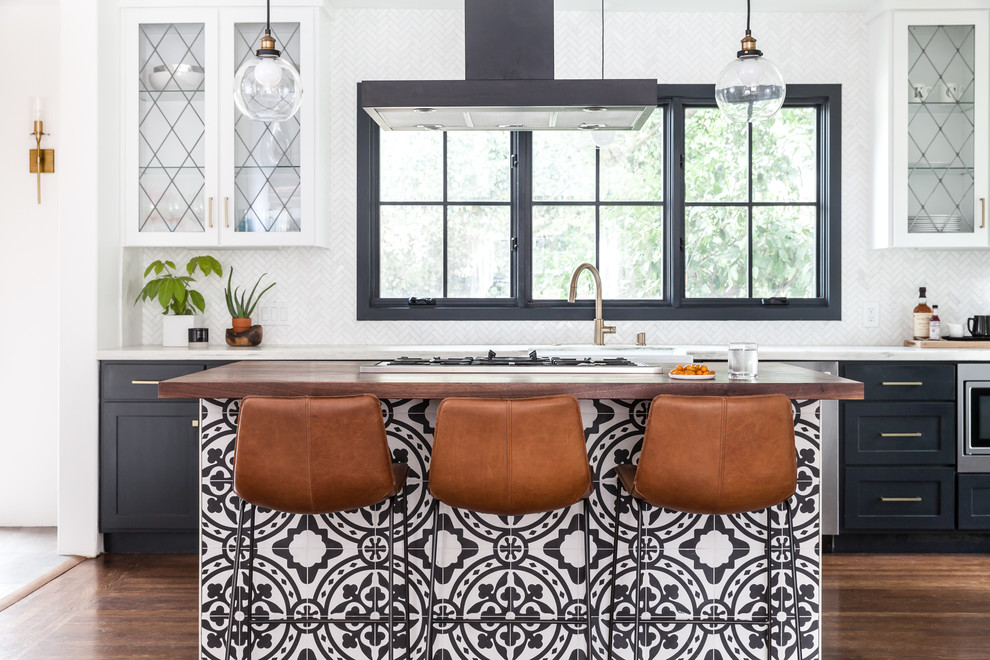 Tuscan galley medium tone wood floor and brown floor kitchen photo in Sacramento with a farmhouse sink, glass-front cabinets, white cabinets, marble countertops, white backsplash, marble backsplash, an island, white countertops and stainless steel appliances