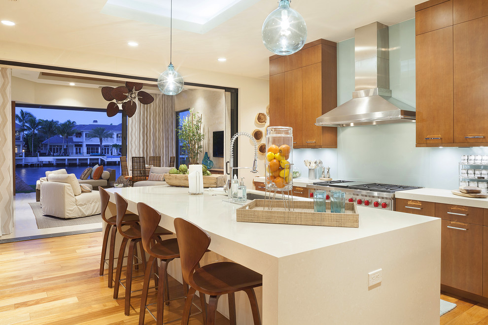 Moderne Küche mit flächenbündigen Schrankfronten, hellbraunen Holzschränken, Küchenrückwand in Blau und Glasrückwand in Miami