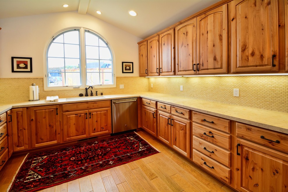 Idée de décoration pour une cuisine sud-ouest américain en bois clair avec un placard à porte shaker, une crédence beige, une crédence en céramique, un électroménager en acier inoxydable et parquet clair.