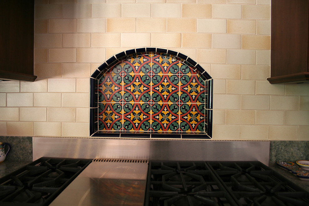 Ejemplo de cocina lineal mediterránea con puertas de armario de madera en tonos medios, encimera de granito, salpicadero amarillo, salpicadero de azulejos de terracota y electrodomésticos de acero inoxidable