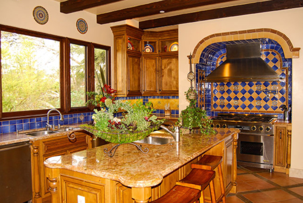 オレンジカウンティにある中くらいな地中海スタイルのおしゃれなキッチン (ダブルシンク、レイズドパネル扉のキャビネット、中間色木目調キャビネット、御影石カウンター、青いキッチンパネル、セラミックタイルのキッチンパネル、シルバーの調理設備) の写真