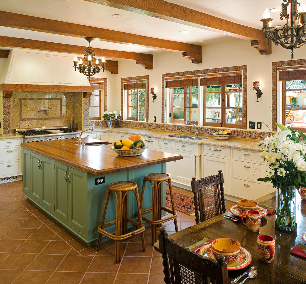 Foto på ett stort lantligt kök, med en undermonterad diskho, luckor med upphöjd panel, gröna skåp, träbänkskiva, stänkskydd i terrakottakakel, rostfria vitvaror, klinkergolv i porslin och en köksö