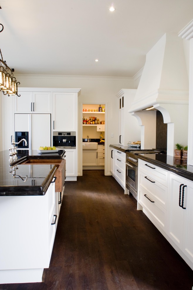 Mediterrane Küche mit Landhausspüle, Schrankfronten mit vertiefter Füllung, weißen Schränken, Granit-Arbeitsplatte und Küchengeräten aus Edelstahl in Los Angeles