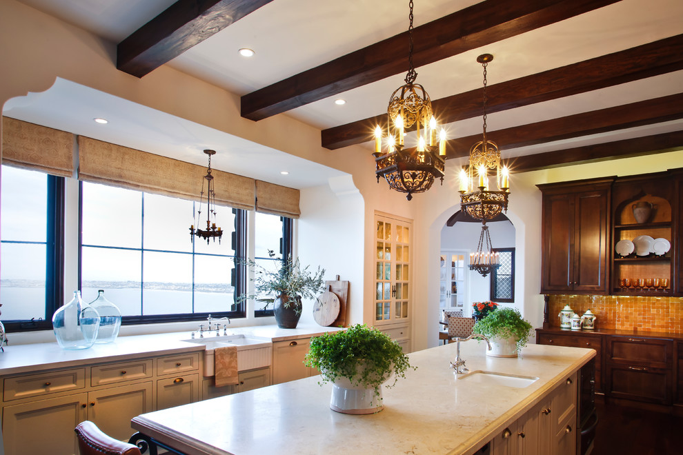 Large tuscan medium tone wood floor and brown floor kitchen photo in Los Angeles with a farmhouse sink, recessed-panel cabinets, beige cabinets, limestone countertops, orange backsplash, ceramic backsplash, paneled appliances, an island and beige countertops