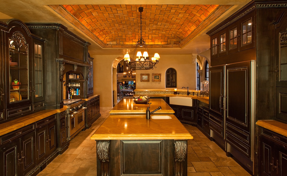 Example of a huge classic galley travertine floor enclosed kitchen design in Phoenix with a farmhouse sink, flat-panel cabinets, dark wood cabinets, granite countertops, beige backsplash, mosaic tile backsplash, paneled appliances and two islands