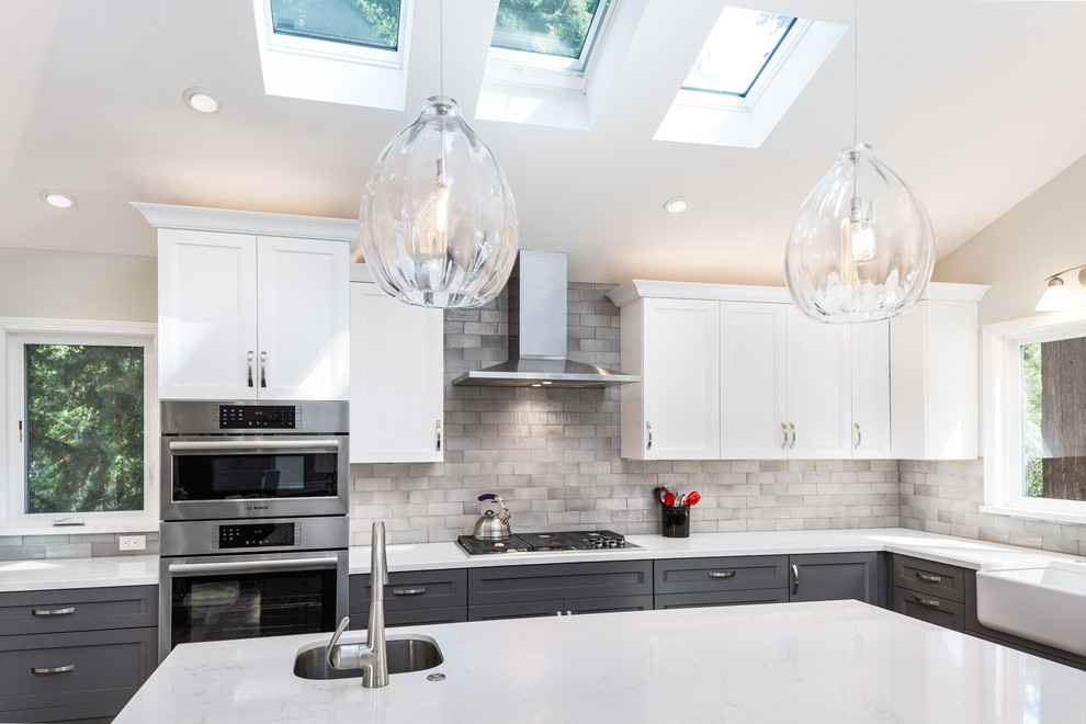 Medium sized classic u-shaped open plan kitchen in Other with a belfast sink, raised-panel cabinets, white cabinets, engineered stone countertops, grey splashback, metro tiled splashback, stainless steel appliances, medium hardwood flooring and an island.