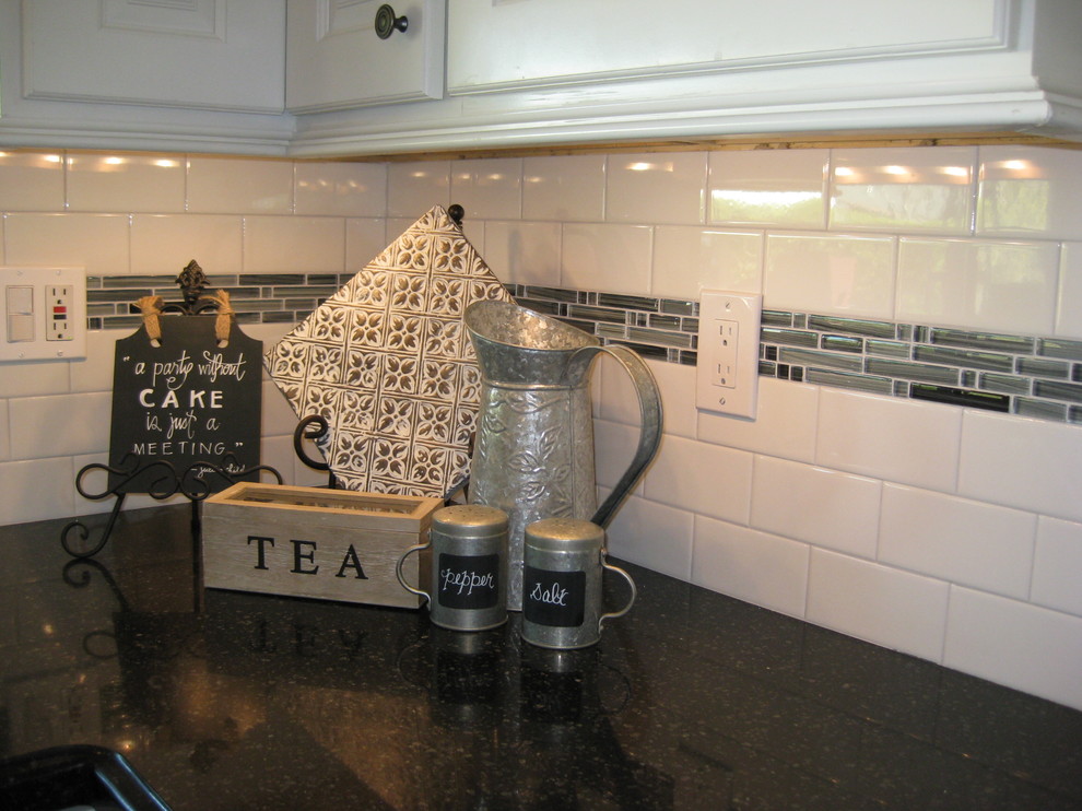 Exempel på ett klassiskt kök, med en undermonterad diskho, luckor med glaspanel, vita skåp, bänkskiva i kvarts, vitt stänkskydd, stänkskydd i porslinskakel och rostfria vitvaror