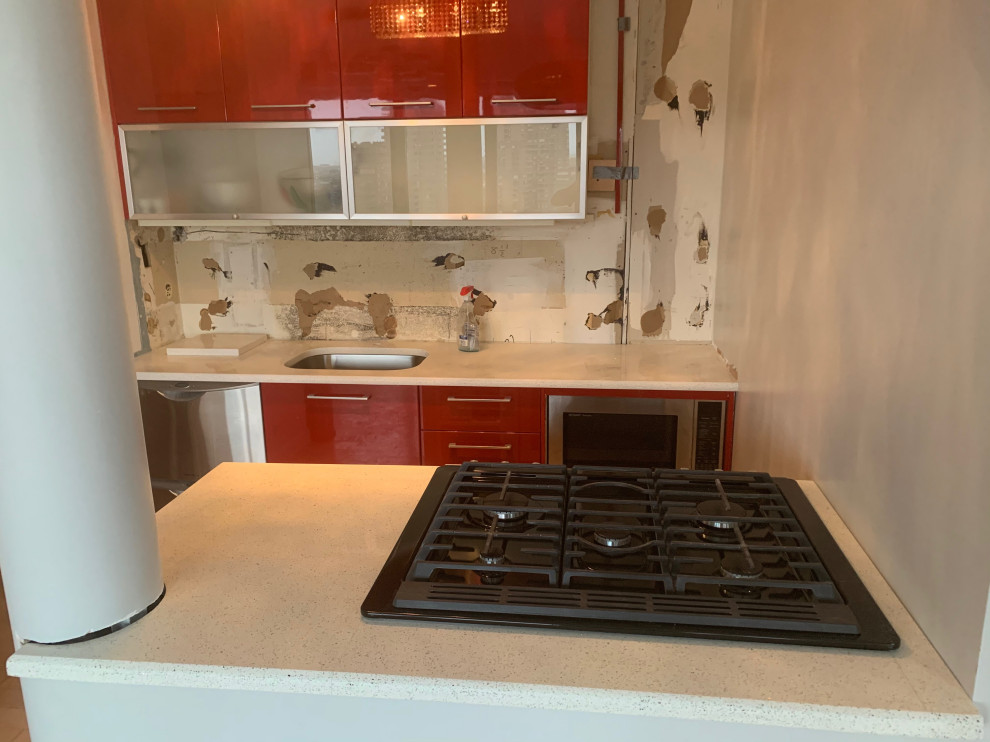 Modelo de cocina minimalista pequeña abierta con armarios con paneles lisos, puertas de armario rojas, encimera de cuarzo compacto, península y encimeras blancas