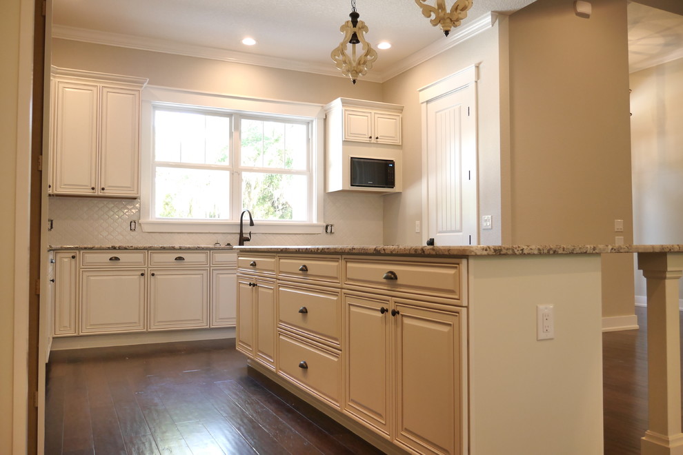 Idéer för att renovera ett shabby chic-inspirerat kök, med en enkel diskho, luckor med upphöjd panel, vita skåp, granitbänkskiva, vitt stänkskydd, stänkskydd i keramik, rostfria vitvaror, mörkt trägolv, en köksö och brunt golv