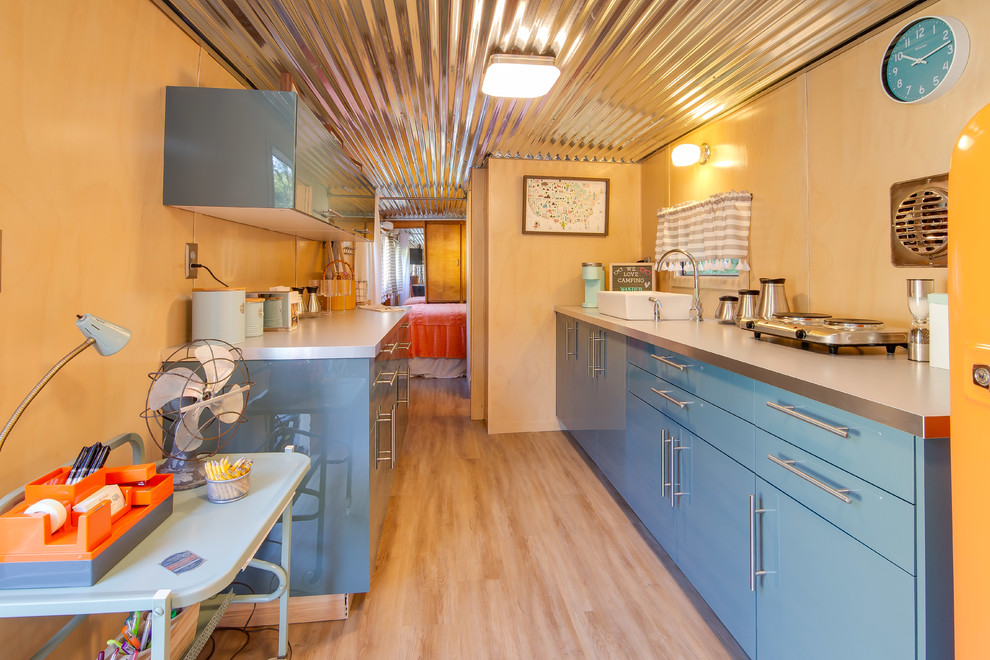 Modelo de cocina vintage pequeña sin isla con armarios con paneles lisos, puertas de armario azules, encimera de acero inoxidable y suelo beige