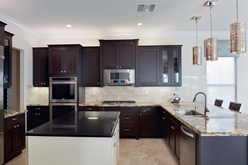 This is an example of a medium sized traditional l-shaped enclosed kitchen in Miami with a built-in sink, glass-front cabinets, black cabinets, granite worktops, beige splashback, stone tiled splashback, stainless steel appliances, marble flooring and a breakfast bar.