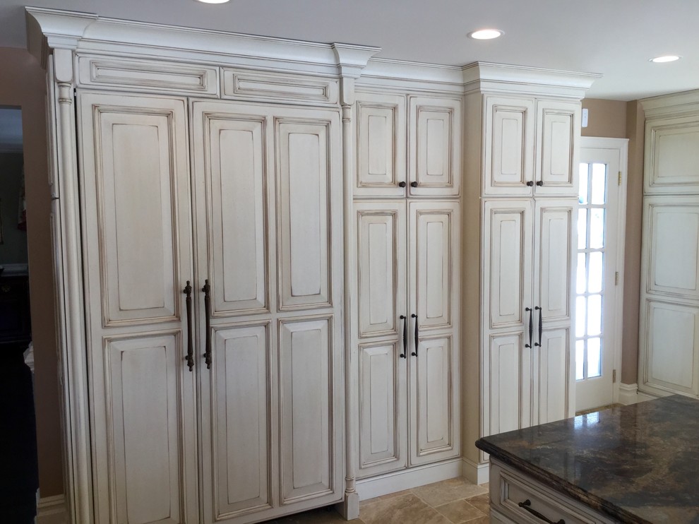 Large elegant u-shaped porcelain tile eat-in kitchen photo in Newark with an undermount sink, raised-panel cabinets, white cabinets, granite countertops, beige backsplash, paneled appliances and an island