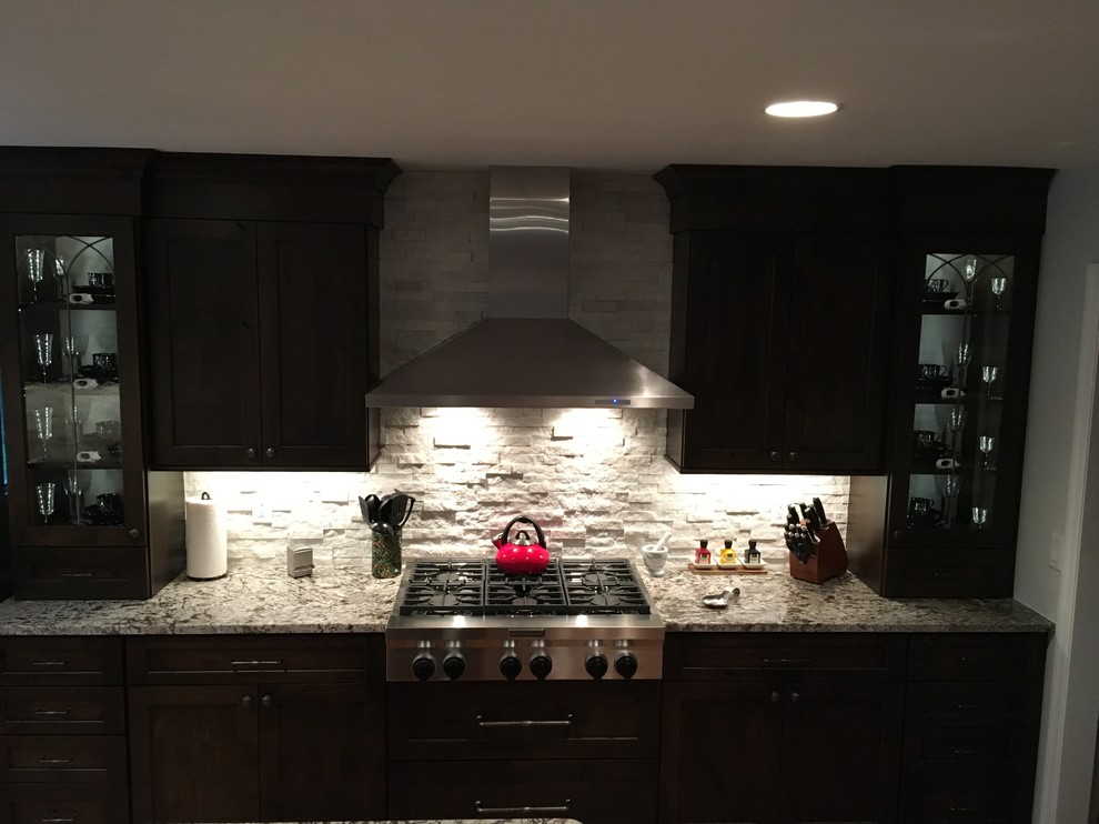 Exempel på ett mellanstort rustikt kök, med en undermonterad diskho, luckor med infälld panel, skåp i mörkt trä, granitbänkskiva, vitt stänkskydd, stänkskydd i stenkakel, rostfria vitvaror, mellanmörkt trägolv och en köksö