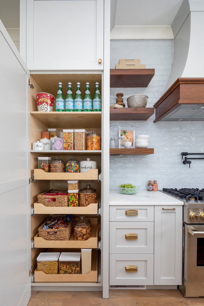 Example of a large beach style l-shaped medium tone wood floor and brown floor kitchen pantry design in Charlotte with a farmhouse sink, gray cabinets, marble countertops, blue backsplash, glass tile backsplash, paneled appliances, an island and white countertops