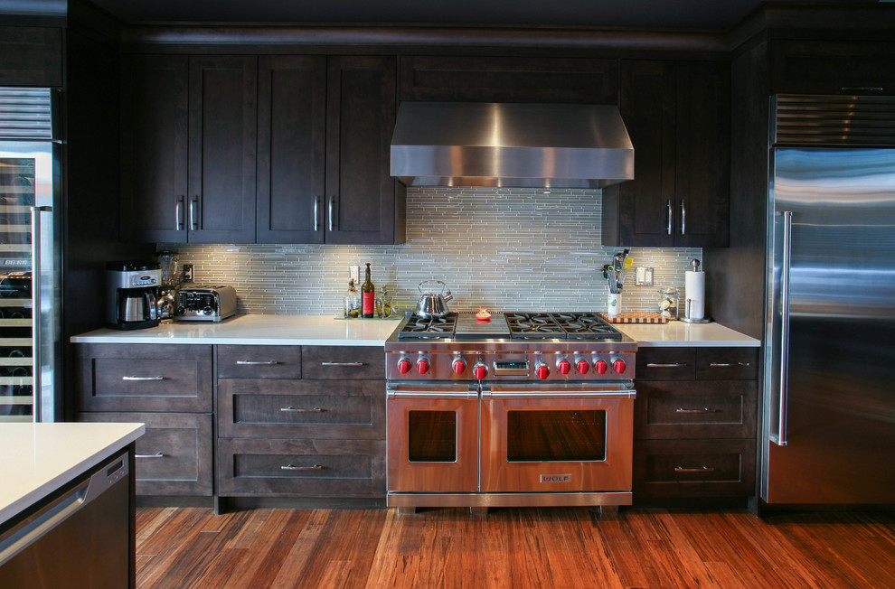 Ejemplo de cocina contemporánea con salpicadero de azulejos de vidrio, electrodomésticos de acero inoxidable, salpicadero verde, armarios estilo shaker y puertas de armario de madera en tonos medios