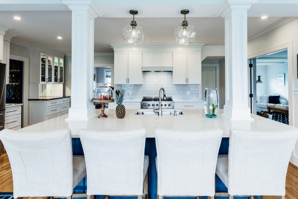 Inspiration for an expansive classic l-shaped kitchen/diner in Providence with a submerged sink, recessed-panel cabinets, white cabinets, quartz worktops, blue splashback, porcelain splashback, stainless steel appliances, medium hardwood flooring, an island and brown floors.