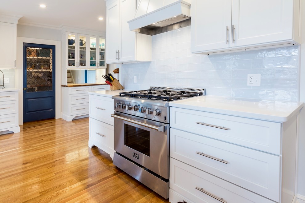 Example of a huge classic l-shaped medium tone wood floor and brown floor eat-in kitchen design in Providence with an undermount sink, recessed-panel cabinets, white cabinets, quartzite countertops, blue backsplash, porcelain backsplash, stainless steel appliances and an island