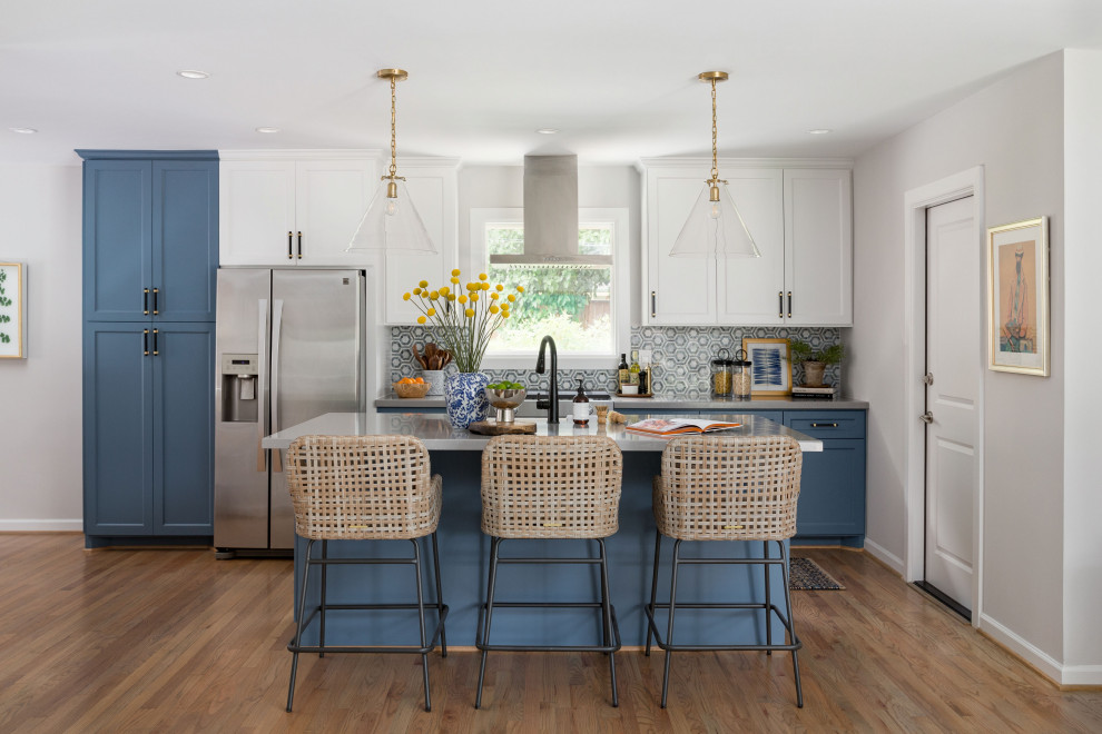 Mid-sized transitional galley medium tone wood floor and brown floor open concept kitchen photo in Houston with a farmhouse sink, shaker cabinets, blue cabinets, quartz countertops, multicolored backsplash, marble backsplash, stainless steel appliances, an island and gray countertops