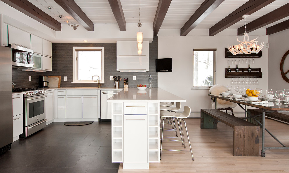 Bild på ett funkis kök och matrum, med en undermonterad diskho, släta luckor, vita skåp, bänkskiva i kvarts, grått stänkskydd, stänkskydd i keramik, rostfria vitvaror och klinkergolv i keramik