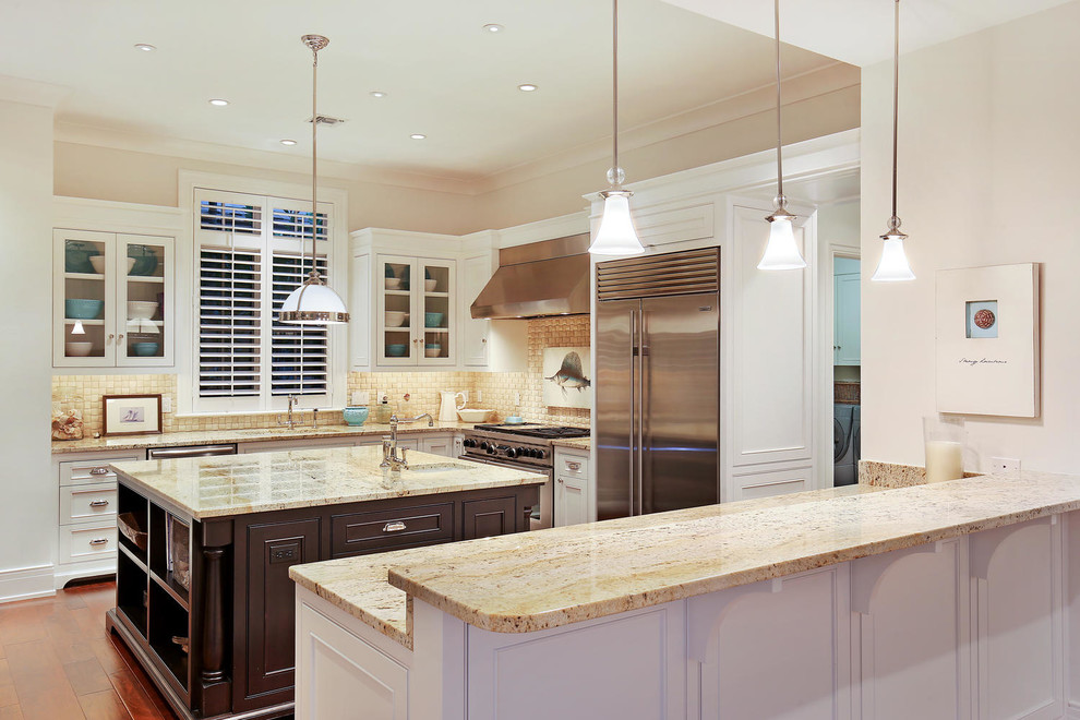 Eat-in kitchen - large tropical u-shaped medium tone wood floor eat-in kitchen idea in Tampa with an undermount sink, recessed-panel cabinets, white cabinets, granite countertops, beige backsplash, mosaic tile backsplash, stainless steel appliances and an island