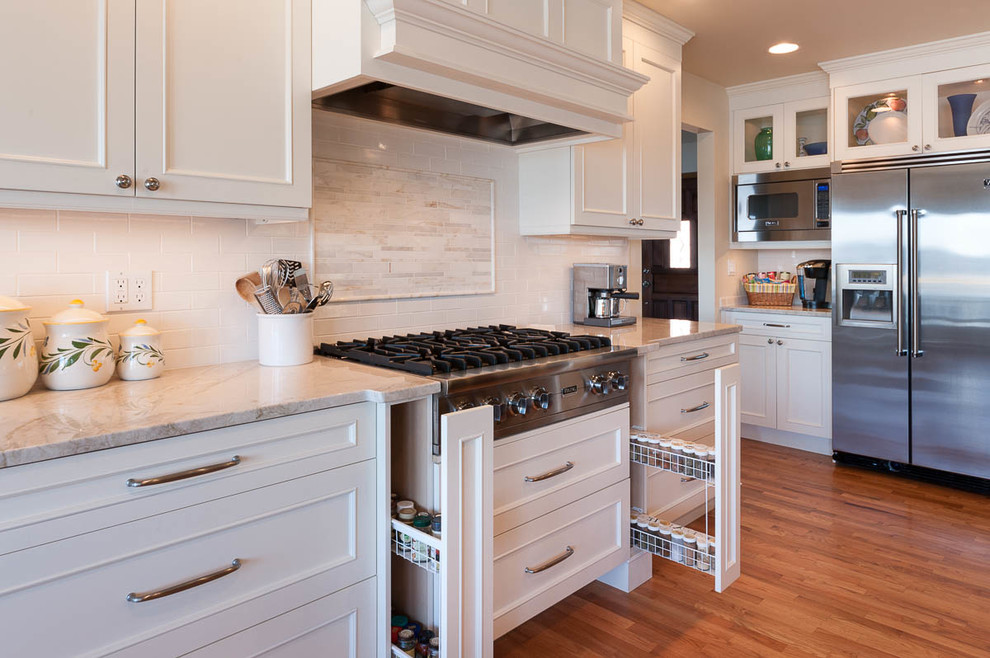 Large arts and crafts l-shaped medium tone wood floor eat-in kitchen photo in Seattle with an undermount sink, shaker cabinets, white cabinets, quartz countertops, white backsplash, subway tile backsplash, stainless steel appliances and an island