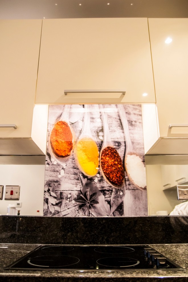 Inspiration for a modern kitchen in Hertfordshire with glass sheet splashback.