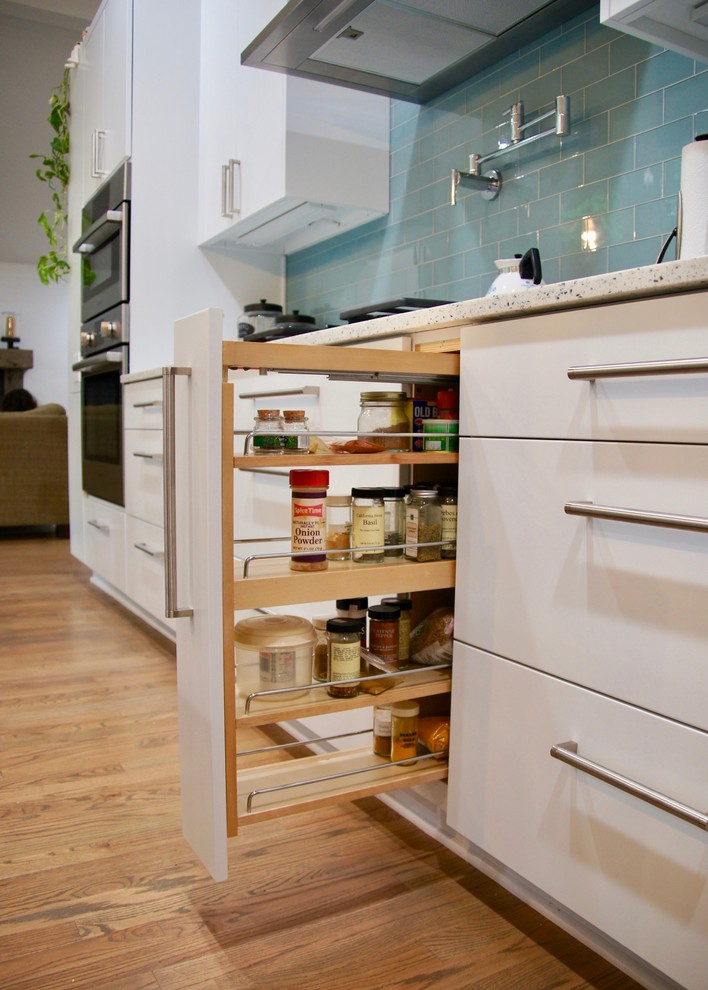 Idéer för att renovera ett mellanstort funkis vit vitt kök, med en undermonterad diskho, släta luckor, vita skåp, bänkskiva i kvarts, blått stänkskydd, stänkskydd i glaskakel, rostfria vitvaror, mellanmörkt trägolv och en köksö