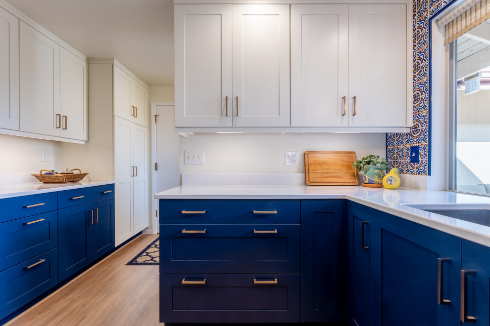 На фото: кухня среднего размера в стиле неоклассика (современная классика) с фасадами в стиле шейкер, синими фасадами, столешницей из кварцевого агломерата, фартуком из керамической плитки и белой столешницей
