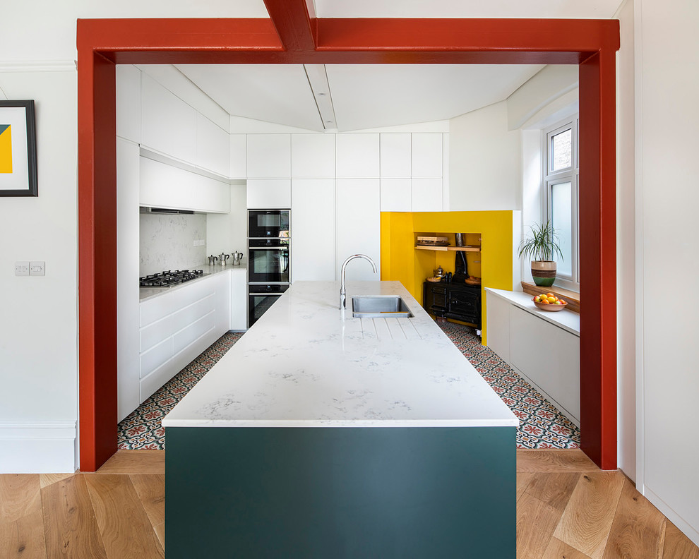 Design ideas for a contemporary u-shaped kitchen in London with a double-bowl sink, flat-panel cabinets, white cabinets, black appliances, ceramic flooring, an island and white worktops.