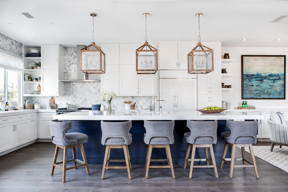 Open concept kitchen - large coastal l-shaped brown floor and dark wood floor open concept kitchen idea in Los Angeles with an undermount sink, shaker cabinets, quartz countertops, white backsplash, marble backsplash, stainless steel appliances, an island, white countertops and white cabinets