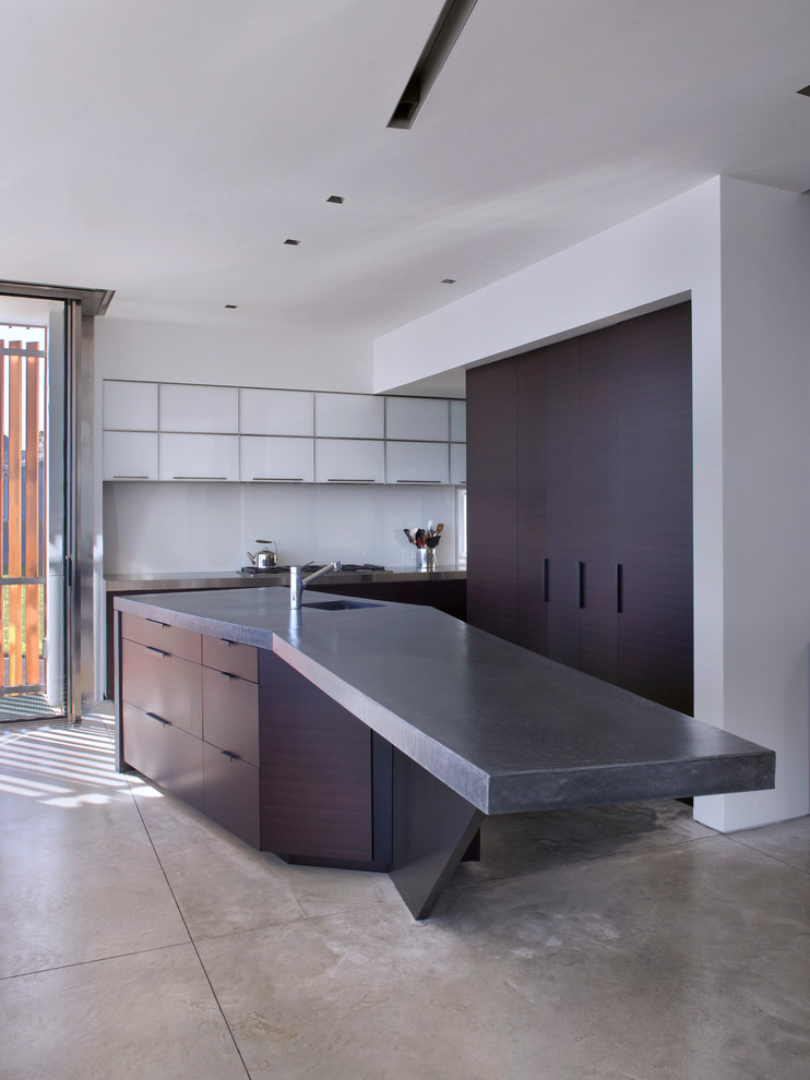 Kitchen - contemporary concrete floor kitchen idea in New York with a single-bowl sink, flat-panel cabinets, concrete countertops, white backsplash, glass sheet backsplash and an island