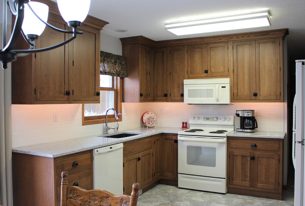 Foto på ett mellanstort vintage kök, med en enkel diskho, skåp i shakerstil, skåp i mellenmörkt trä, bänkskiva i kvarts, vitt stänkskydd, stänkskydd i tunnelbanekakel och vita vitvaror