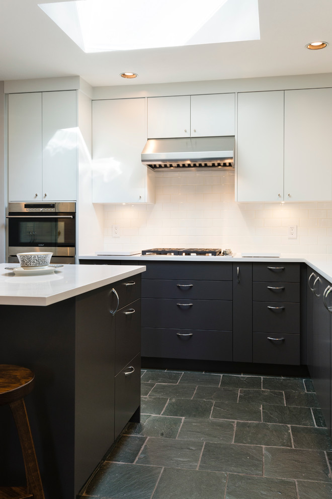 Enclosed kitchen - mid-sized transitional slate floor enclosed kitchen idea in Vancouver with an undermount sink, flat-panel cabinets, black cabinets, quartz countertops, white backsplash, subway tile backsplash, stainless steel appliances and an island