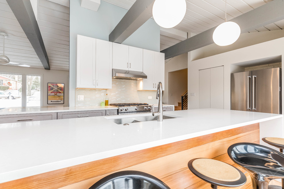 Exempel på ett mellanstort 60 tals kök, med en undermonterad diskho, skåp i shakerstil, gröna skåp, bänkskiva i kvarts, blått stänkskydd, stänkskydd i keramik, rostfria vitvaror, mellanmörkt trägolv, en köksö och brunt golv