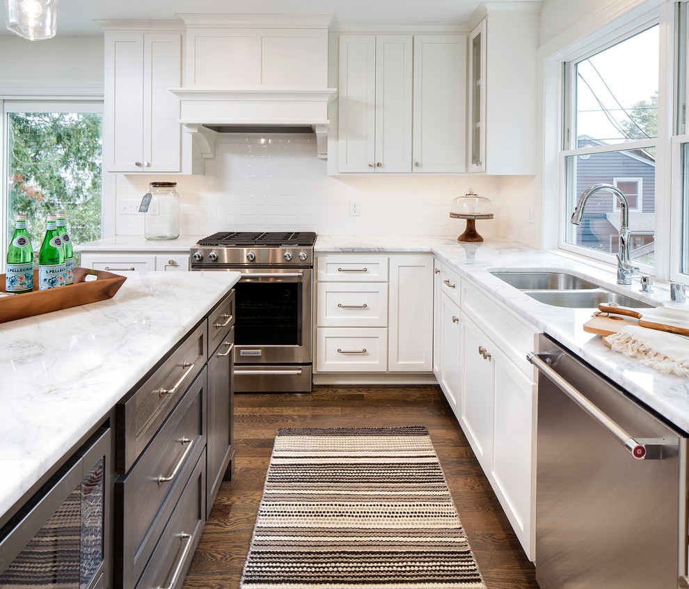 Klassisk inredning av ett mellanstort kök, med en undermonterad diskho, skåp i shakerstil, vita skåp, marmorbänkskiva, rostfria vitvaror, mörkt trägolv och en köksö