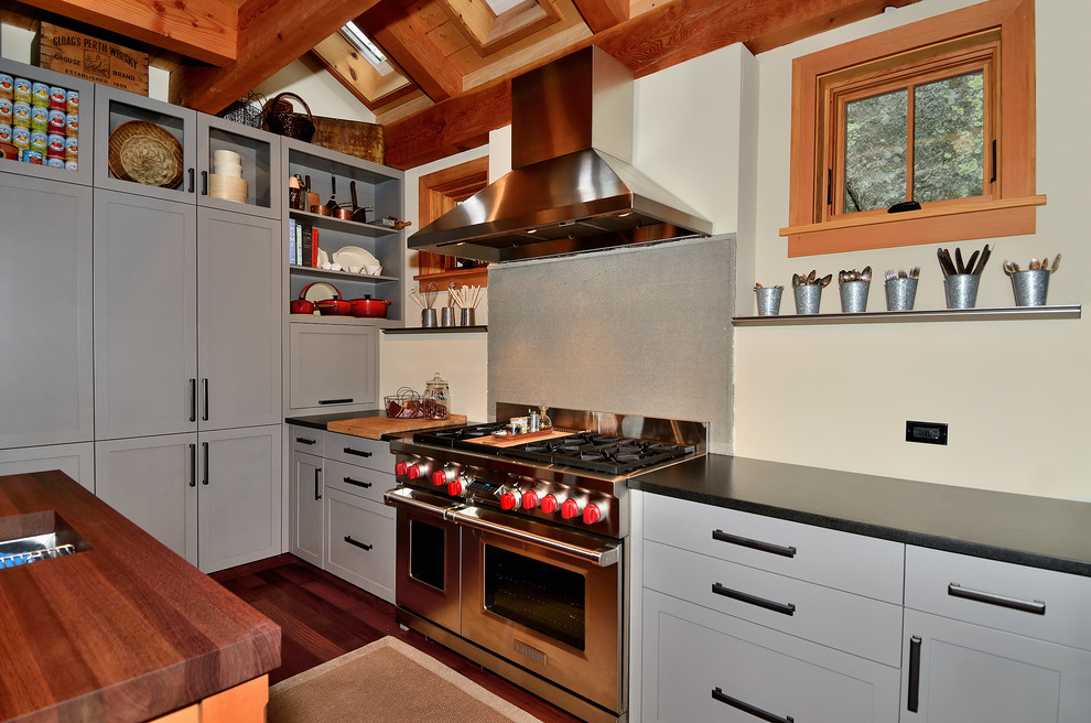 Moderne Küche in U-Form mit Küchengeräten aus Edelstahl, Schrankfronten im Shaker-Stil, grauen Schränken, Landhausspüle, braunem Holzboden und Kücheninsel in Burlington