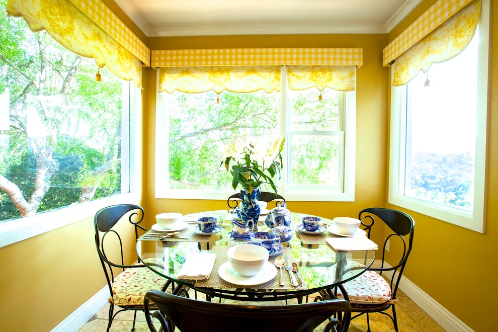 На фото: угловая кухня среднего размера в классическом стиле с обеденным столом, с полувстраиваемой мойкой (с передним бортиком), фасадами в стиле шейкер, бежевыми фасадами, гранитной столешницей, желтым фартуком, техникой из нержавеющей стали и полом из известняка