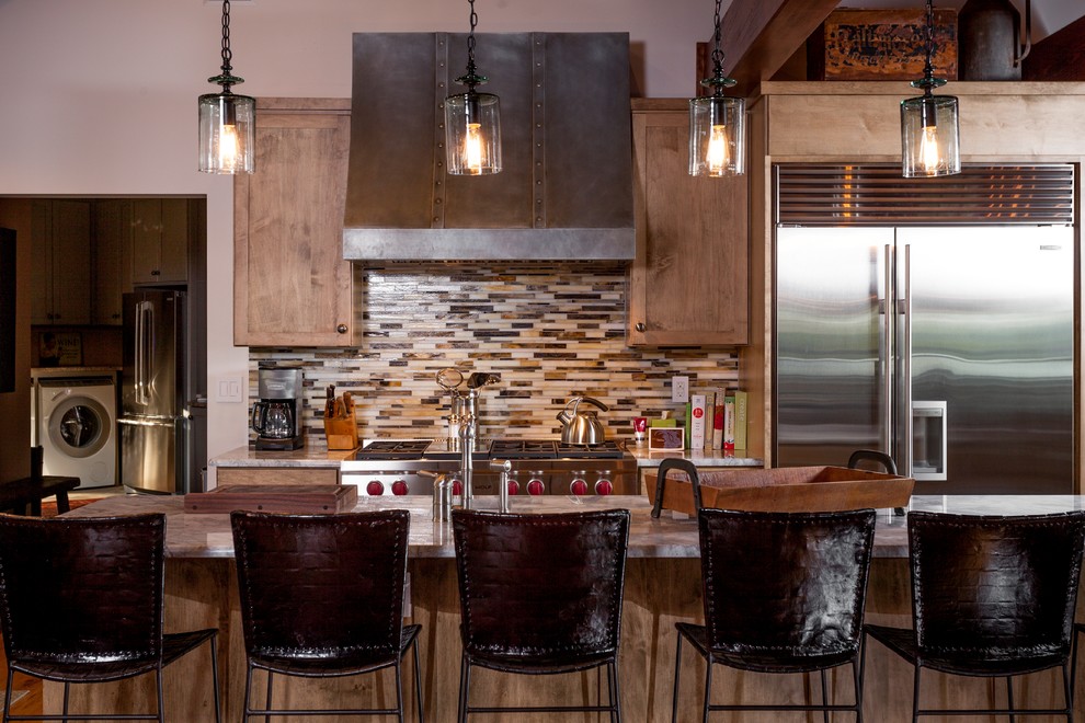 Exemple d'une cuisine américaine linéaire montagne en bois brun de taille moyenne avec un placard à porte shaker, un plan de travail en granite, une crédence beige, une crédence en carreau briquette, un électroménager en acier inoxydable et îlot.