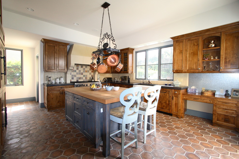 Inspiration for a large farmhouse u-shaped ceramic tile and brown floor eat-in kitchen remodel with a farmhouse sink, shaker cabinets, medium tone wood cabinets, wood countertops, white backsplash, porcelain backsplash, stainless steel appliances and an island
