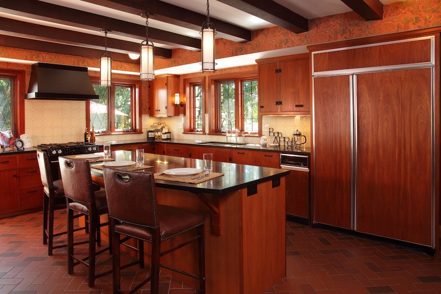 Exemple d'une cuisine américaine encastrable chic en L et bois brun de taille moyenne avec un évier encastré, un placard à porte plane, un sol en brique, îlot et un sol rouge.