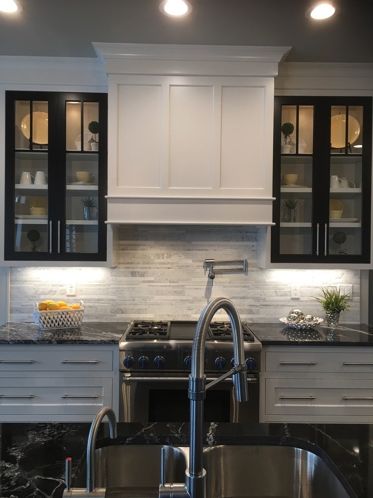 Medium sized traditional l-shaped enclosed kitchen in Milwaukee with white cabinets, granite worktops, white splashback, marble splashback, stainless steel appliances, an island, a double-bowl sink and beaded cabinets.