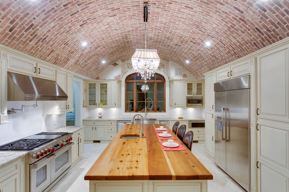 Inspiration för ett avskilt medelhavsstil u-kök, med en rustik diskho, luckor med upphöjd panel, beige skåp, rostfria vitvaror och en köksö