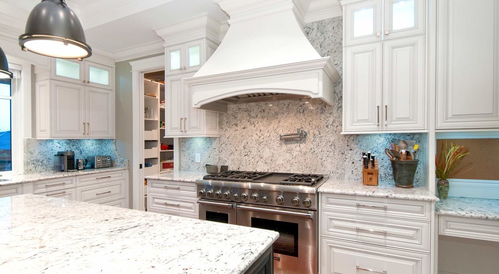 Foto på ett mellanstort maritimt vit kök, med en dubbel diskho, skåp i shakerstil, vita skåp, granitbänkskiva, vitt stänkskydd, stänkskydd i sten, rostfria vitvaror, klinkergolv i porslin, en köksö och grått golv