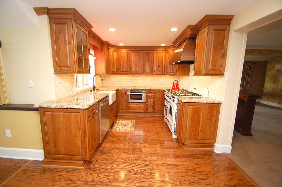 Example of a mid-sized classic u-shaped medium tone wood floor eat-in kitchen design in New York with a farmhouse sink, raised-panel cabinets, medium tone wood cabinets, granite countertops, white backsplash, subway tile backsplash, stainless steel appliances and no island