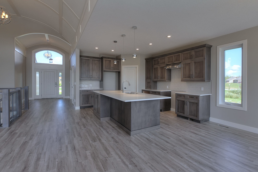 This is an example of a medium sized traditional l-shaped open plan kitchen in Edmonton with a submerged sink, shaker cabinets, grey cabinets, limestone worktops, white splashback, stainless steel appliances, painted wood flooring and an island.