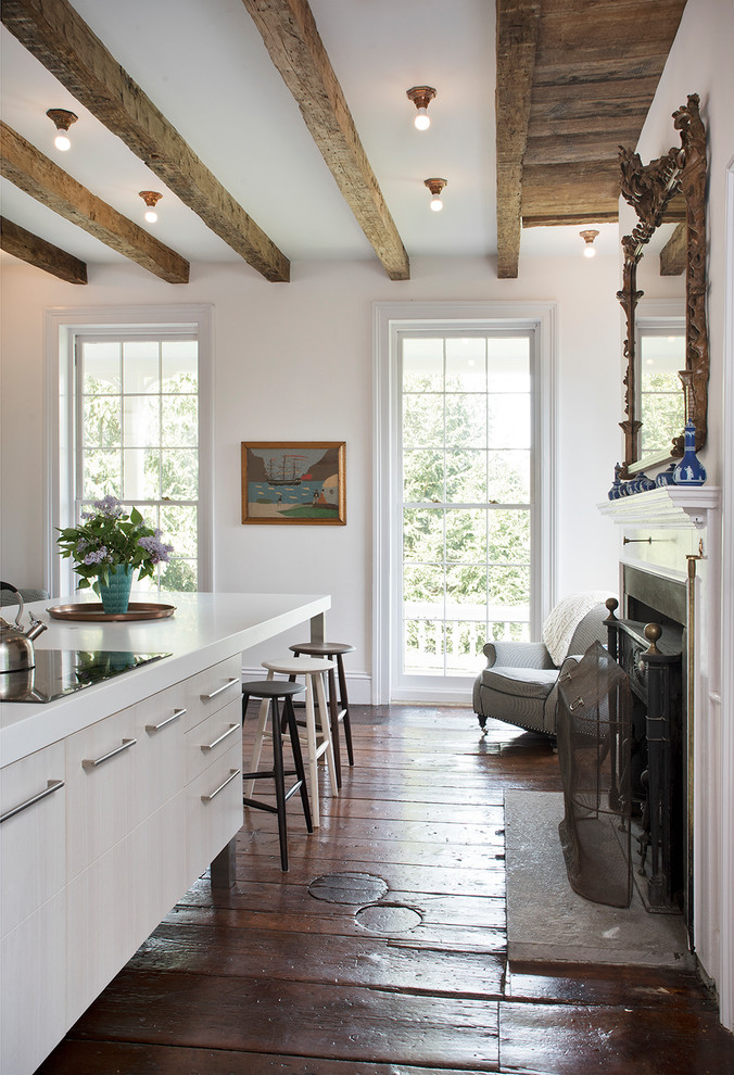 Cette image montre une grande cuisine américaine traditionnelle en L avec un placard à porte plane, des portes de placard blanches, un plan de travail en quartz modifié, parquet foncé, îlot et un sol marron.