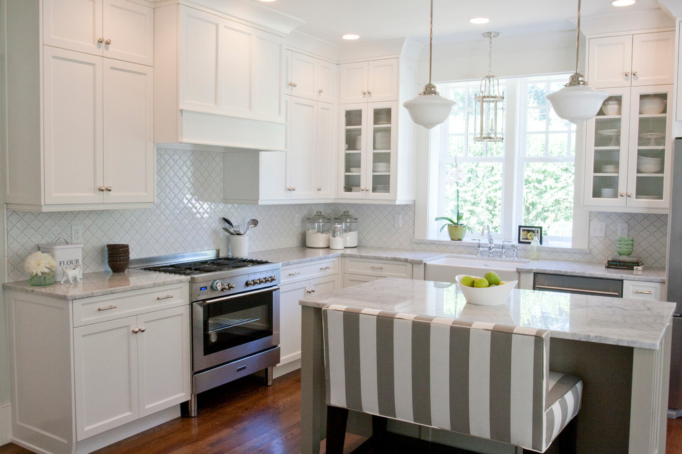 Elegant l-shaped kitchen photo in Salt Lake City with glass-front cabinets, a farmhouse sink, stainless steel appliances, white cabinets and white backsplash