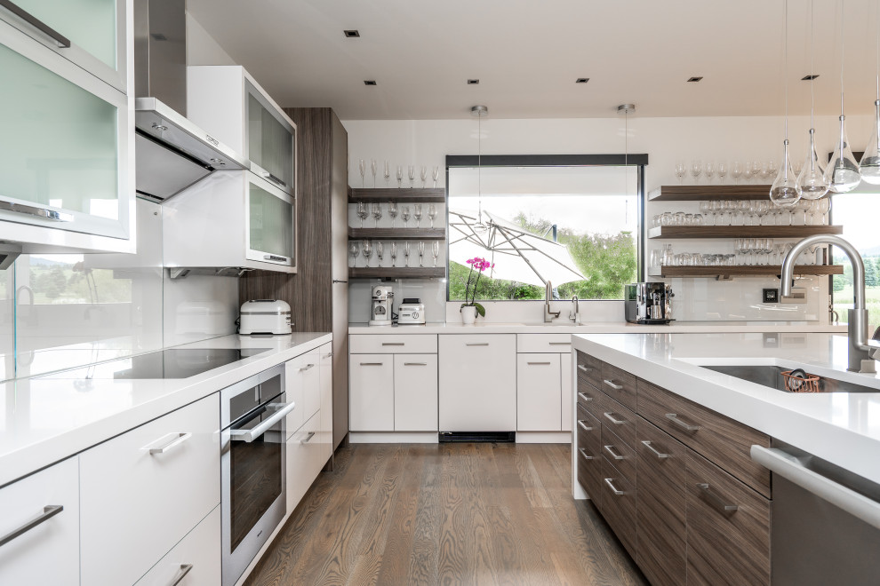 Esempio di una cucina design con lavello sottopiano, ante lisce, ante bianche, elettrodomestici in acciaio inossidabile, parquet scuro, pavimento marrone e top bianco