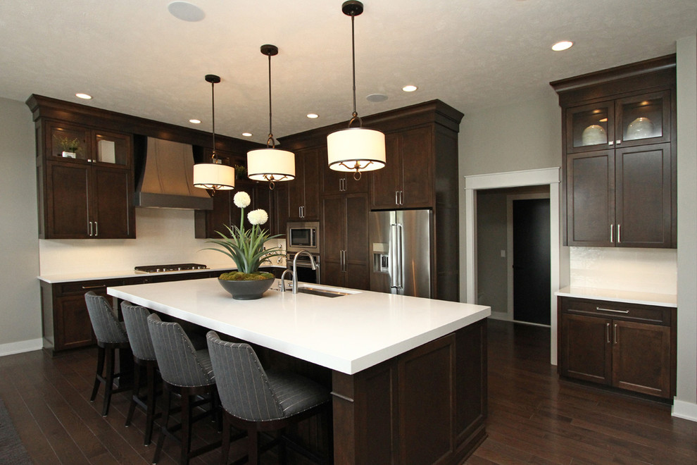 Mid-sized transitional l-shaped dark wood floor and brown floor eat-in kitchen photo in Other with an undermount sink, dark wood cabinets, quartz countertops, white backsplash, stainless steel appliances, an island, recessed-panel cabinets, stone slab backsplash and white countertops